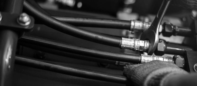 This image shows an engineer working on some hydraulic fittings with a spanner.